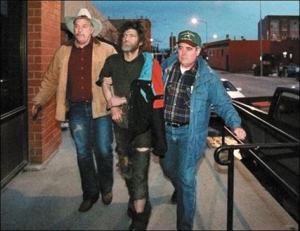 Theodore Kaczynski is escorted by two FBI officers into a Helena office building on the night of his arrest in 1996. Printed with permission from photographer Greg Rec