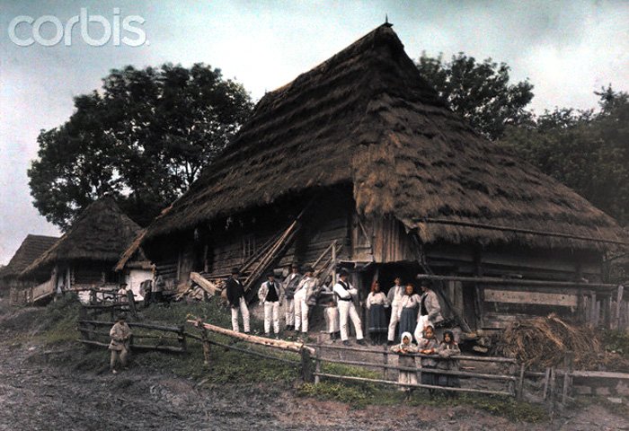 1927, Ruthenia, Ukraine --- A large group of peasants stand outside their thatch-roof homes --- Image by © Hans Hildenbrand/National Geographic Society/Corbis